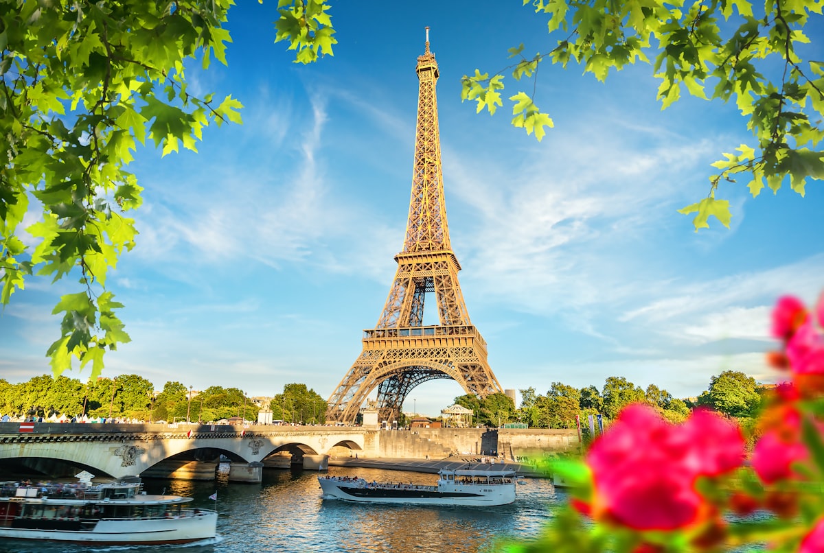 The Eiffel Tower framed by spring flowers and green leaves on a sunny day in Paris, France