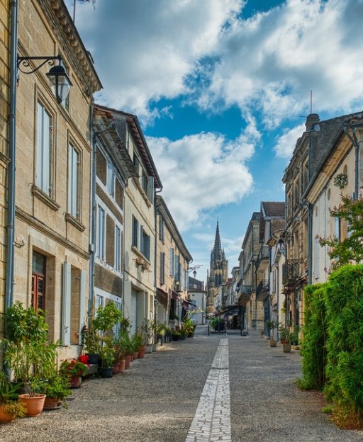 Cobblestone street in Cadillac, Gironde, Aquitaine, France, with a church steeple in the background