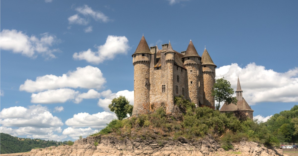 Château de Val rising from Lac de Bort-les-Orgues, Cantal, Auvergne, France