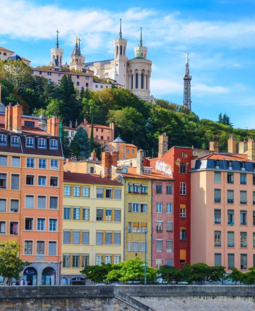 Colourful houses along the Saône river in Lyon with the Fourvière Basilica on the hill above