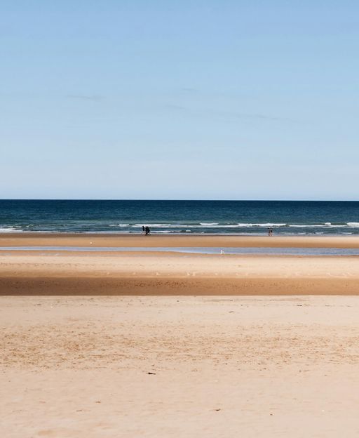Wide sandy beach at Normandy, France — one of the D-Day landing beaches, peaceful and vast under a clear blue sky