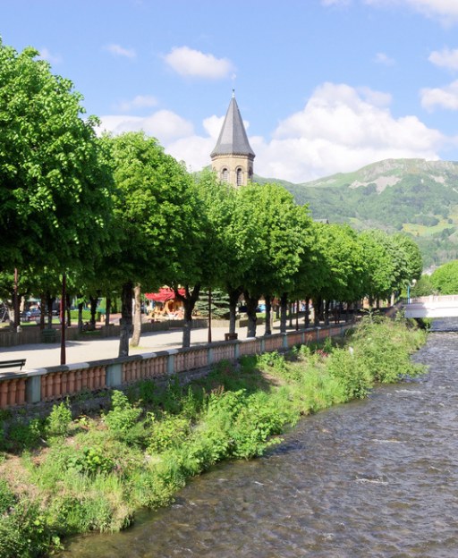 La Bourboule village in France, a charming spa town with a tree-lined river and church spire