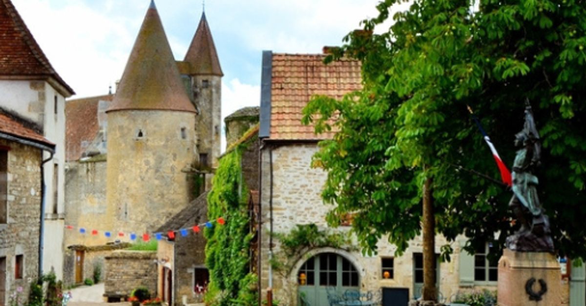 Medieval stone towers and ivy-covered buildings in a French village square