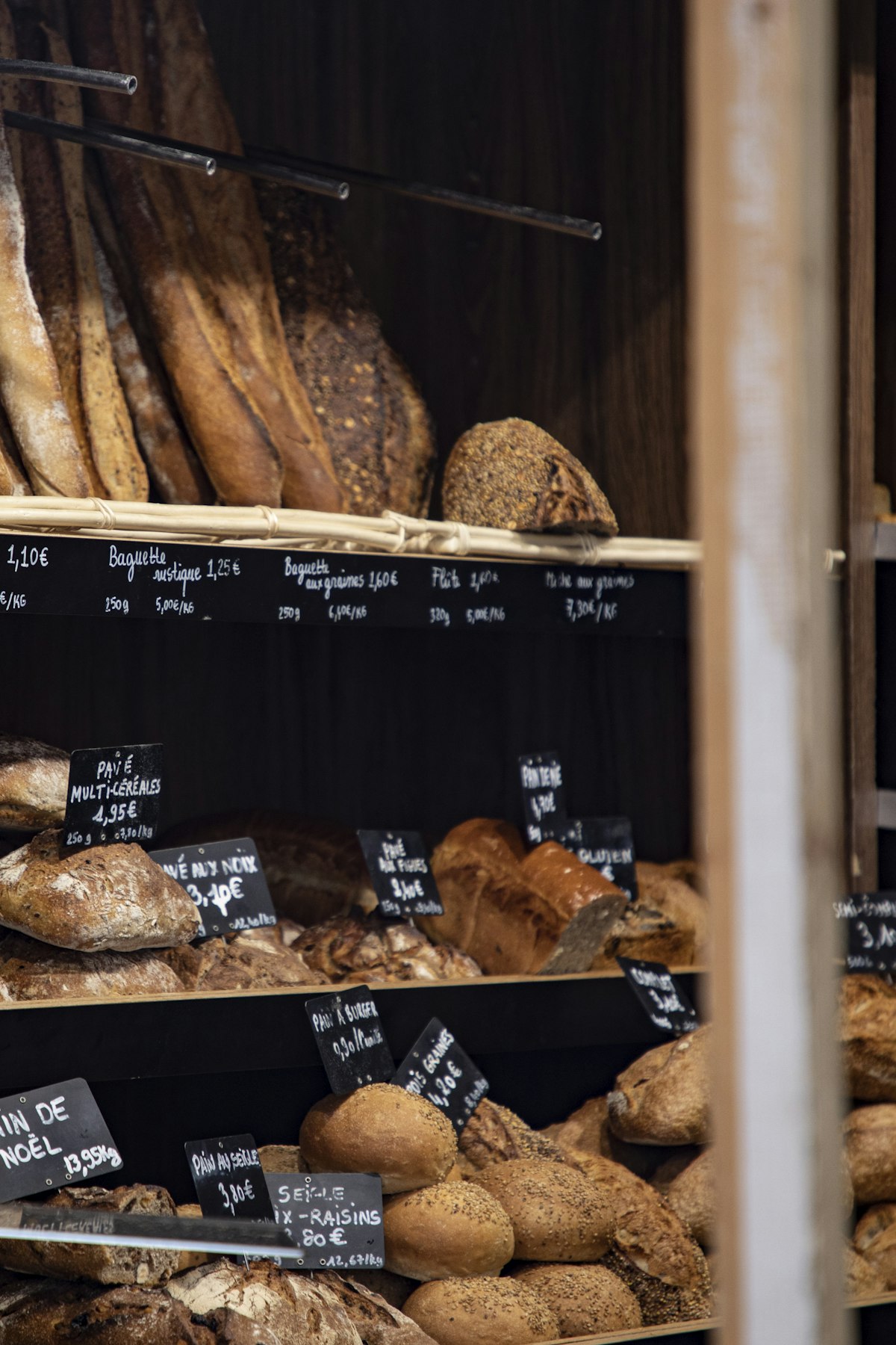 Shelves displaying various artisan breads with French price labels and chalkboard signs