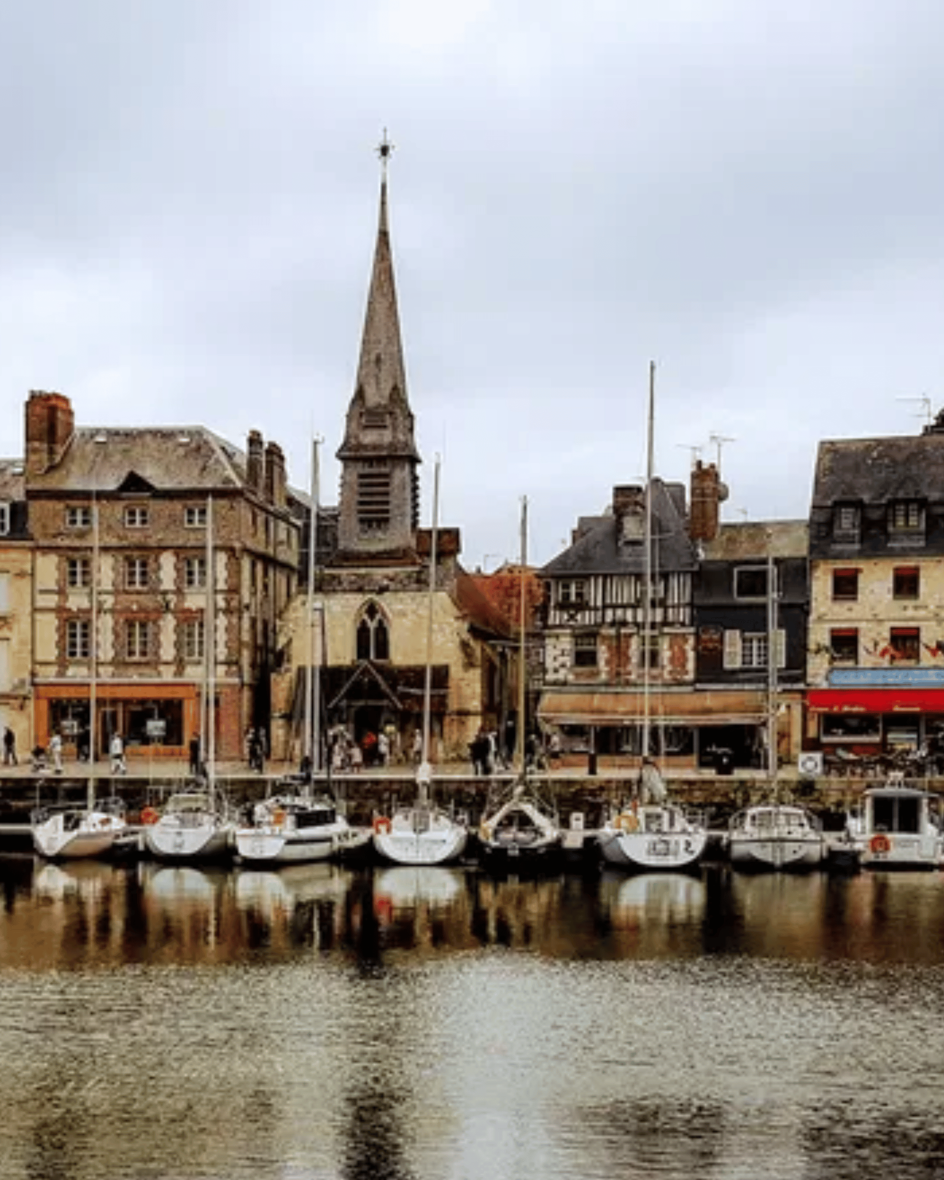 Sailboats moored in harbor with church spire and historic waterfront buildings