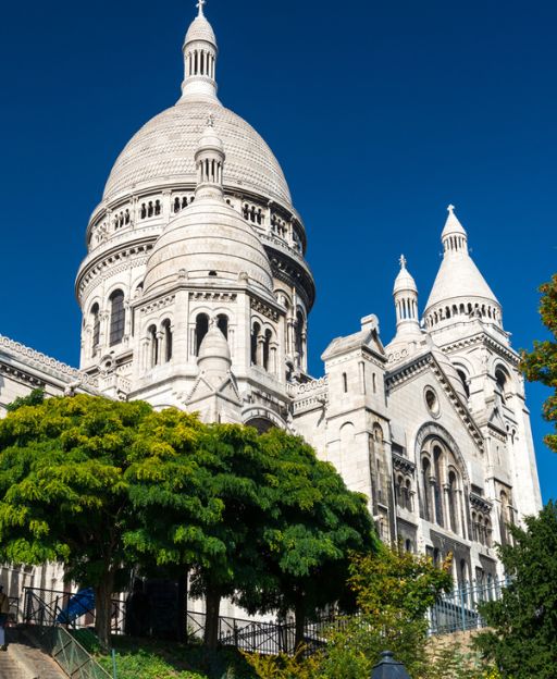 White domed basilica with Romano-Byzantine architecture and green trees below