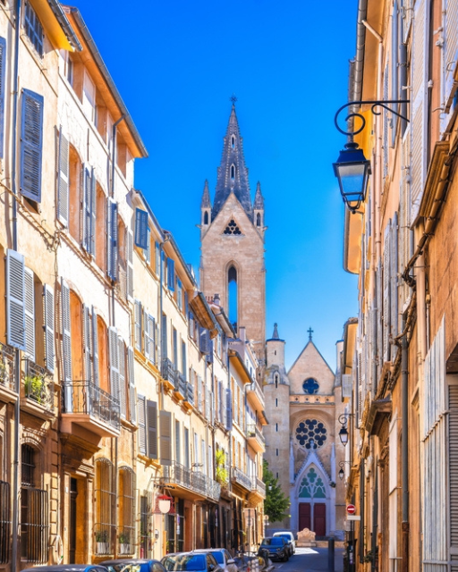 Narrow European street lined with pastel buildings leading to a church spire