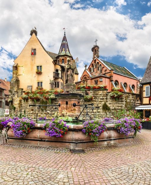 Colorful half-timbered buildings with purple flowers in Alsatian town square