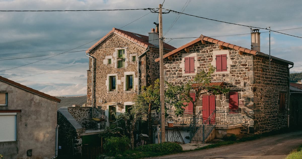 Stone farmhouses with red shutters and terracotta roof tiles in rural French village