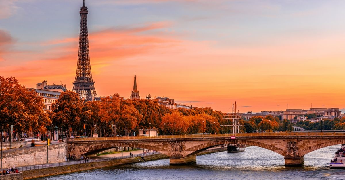Eiffel Tower at sunset with autumn trees and Seine river bridge