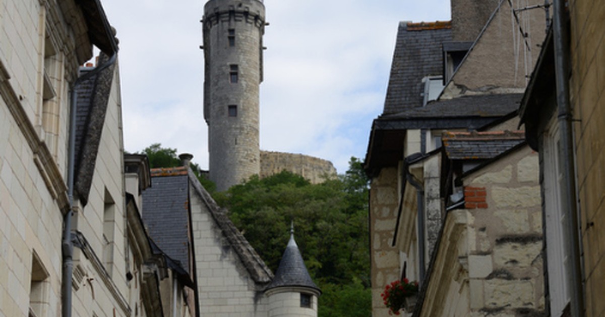 Medieval stone tower rises above narrow cobblestone street lined with historic buildings