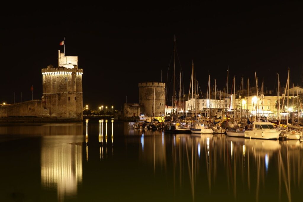 Tour Saint-Nicolas and Tour de la Chaîne lit up at night above the old port of La Rochelle