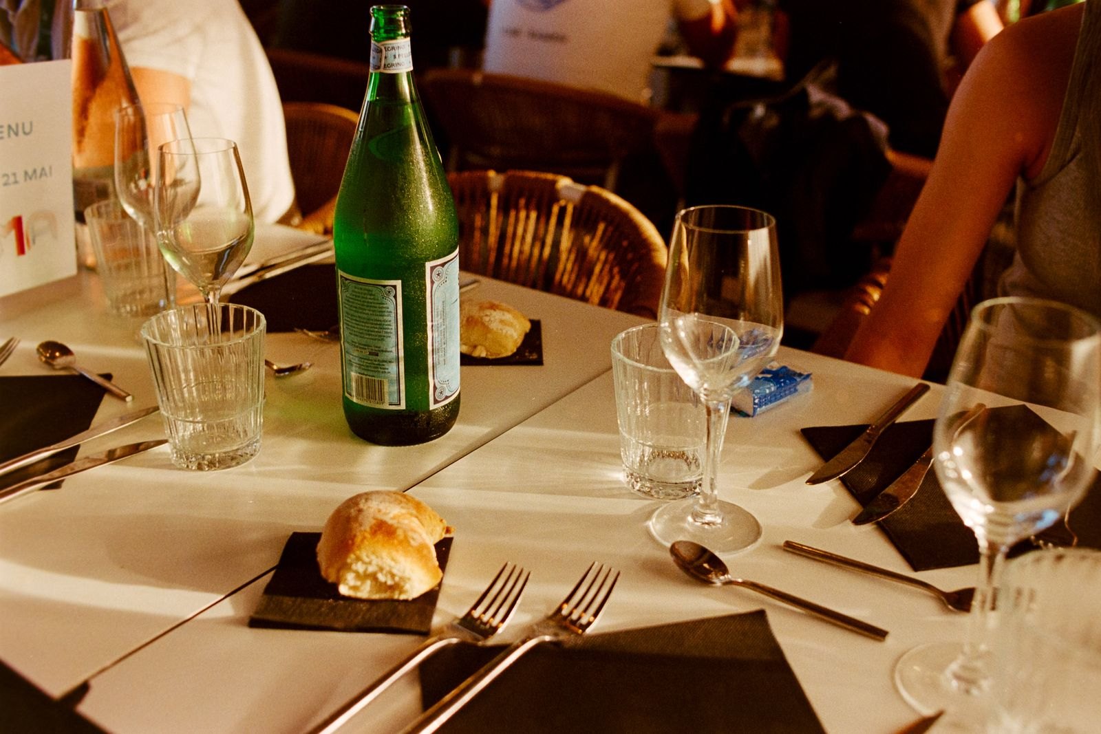 A table set with bread, water and wine glasses in a French café