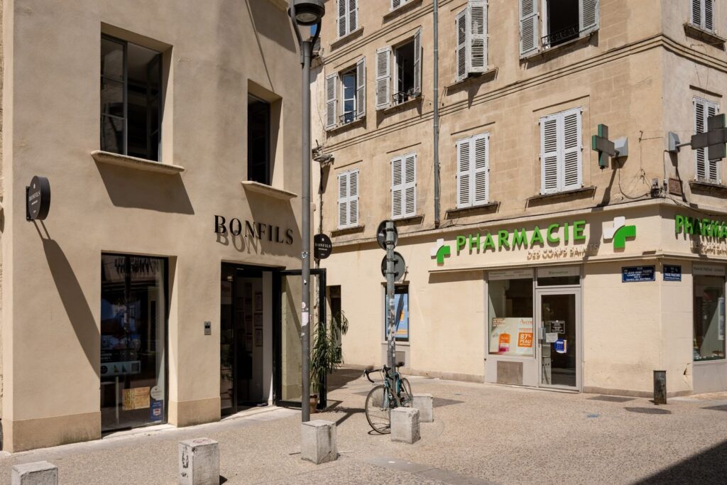 A pharmacie with its green cross on a street in southern France