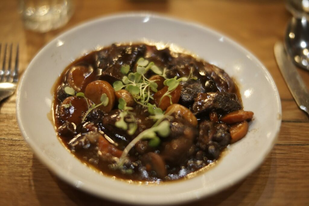 A bowl of beef stewed in red wine with mushrooms and carrots