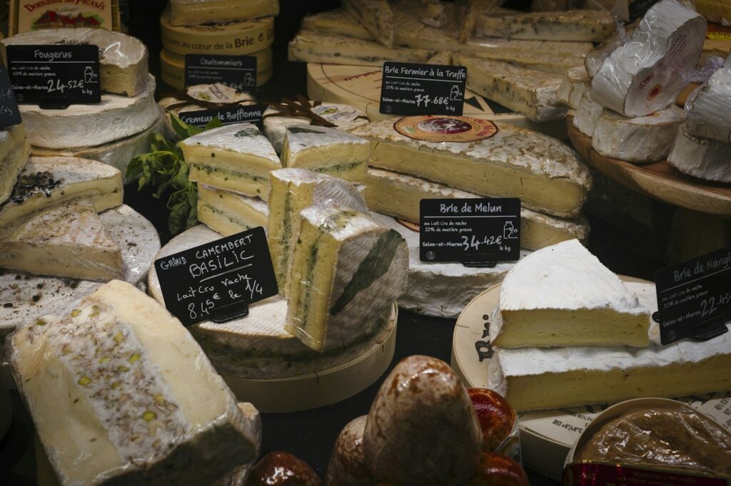 Soft and hard French cheeses with price labels on a market stall