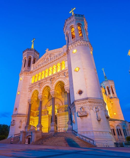 The Basilica of Fourvière illuminated at blue hour above the Saône river in Lyon, France