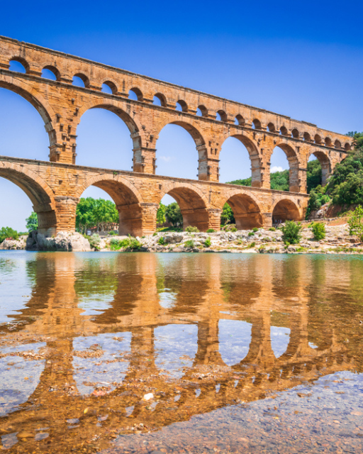 The Pont du Gard Roman aqueduct reflected in the Gardon River, southern France
