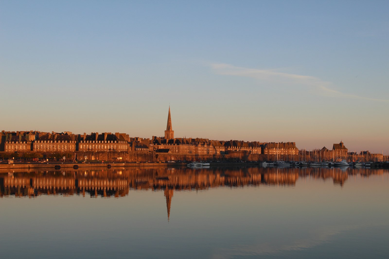 Saint-Malo's walled old town and cathedral spire reflected in the harbour at sunrise