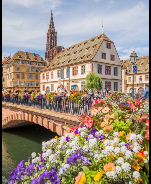 Colorful flowers on bridge overlooking half-timbered buildings and cathedral spire