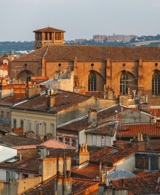 Terracotta rooftops and historic brick buildings in golden afternoon light, Toulouse